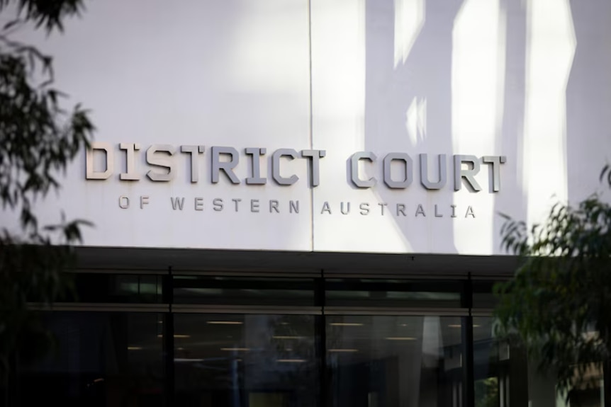 A medium shot with a sign reading: District Court of Western Australia.