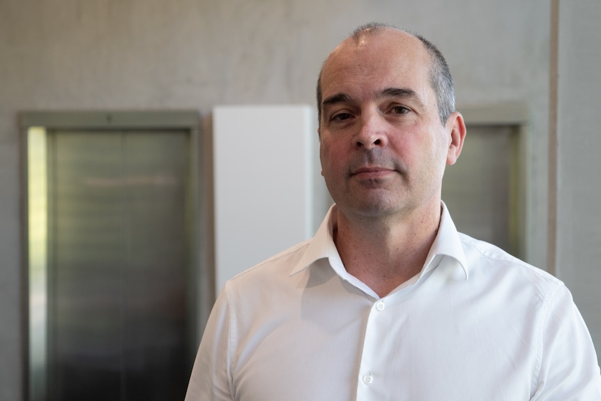 Man in white shirt looks at camera