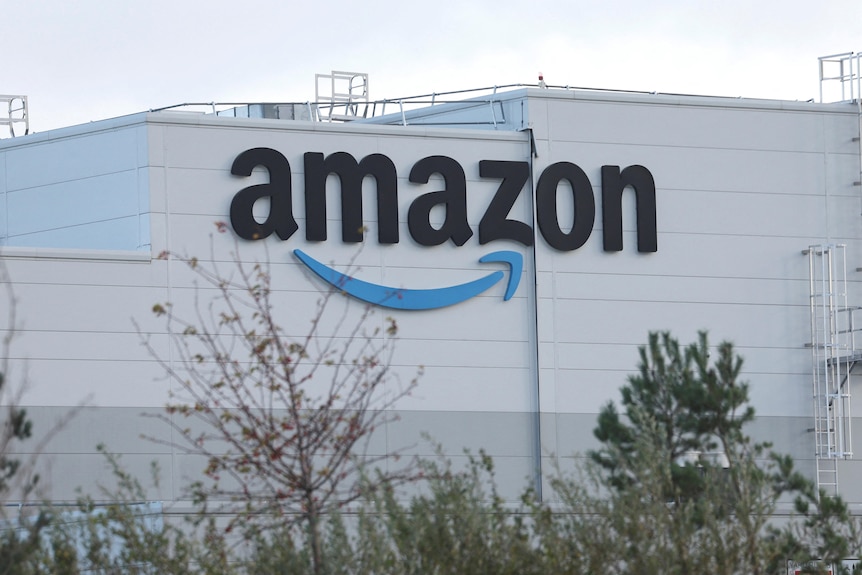 An Amazon logo on the side of a large warehouse building.