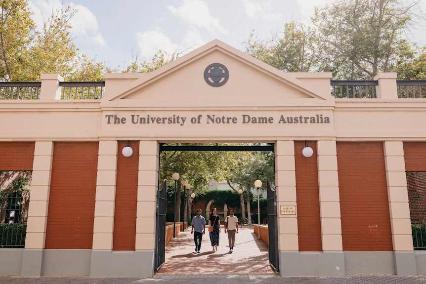 Three people walk through Notre Dame University Australia campus.