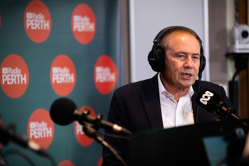 A mid-shot of WA Premier Roger Cook speaking in a radio studio with headphones on.