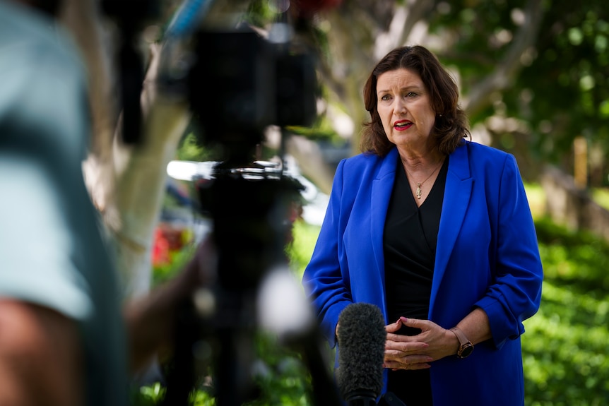 A woman in a blue jacket speaks to a camera