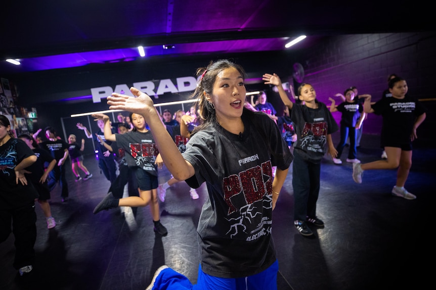 A woman with a dark tshirt dancing in a dark room with a group of other people