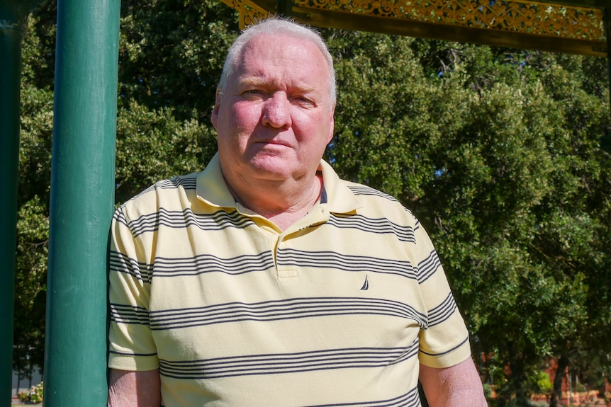 A man leaning against a pole.