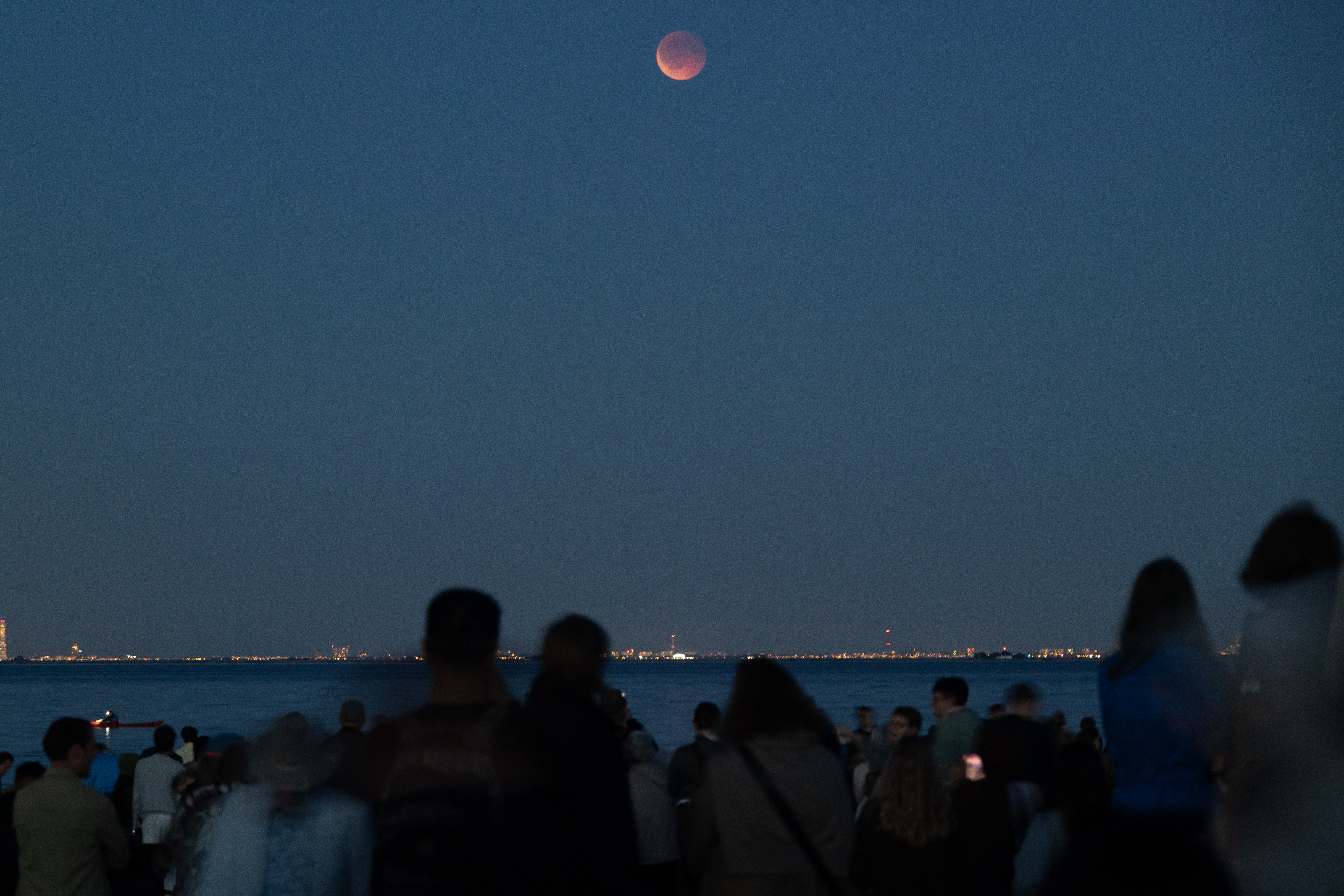 group of people watching a blood red moon during total lunar eclipse.