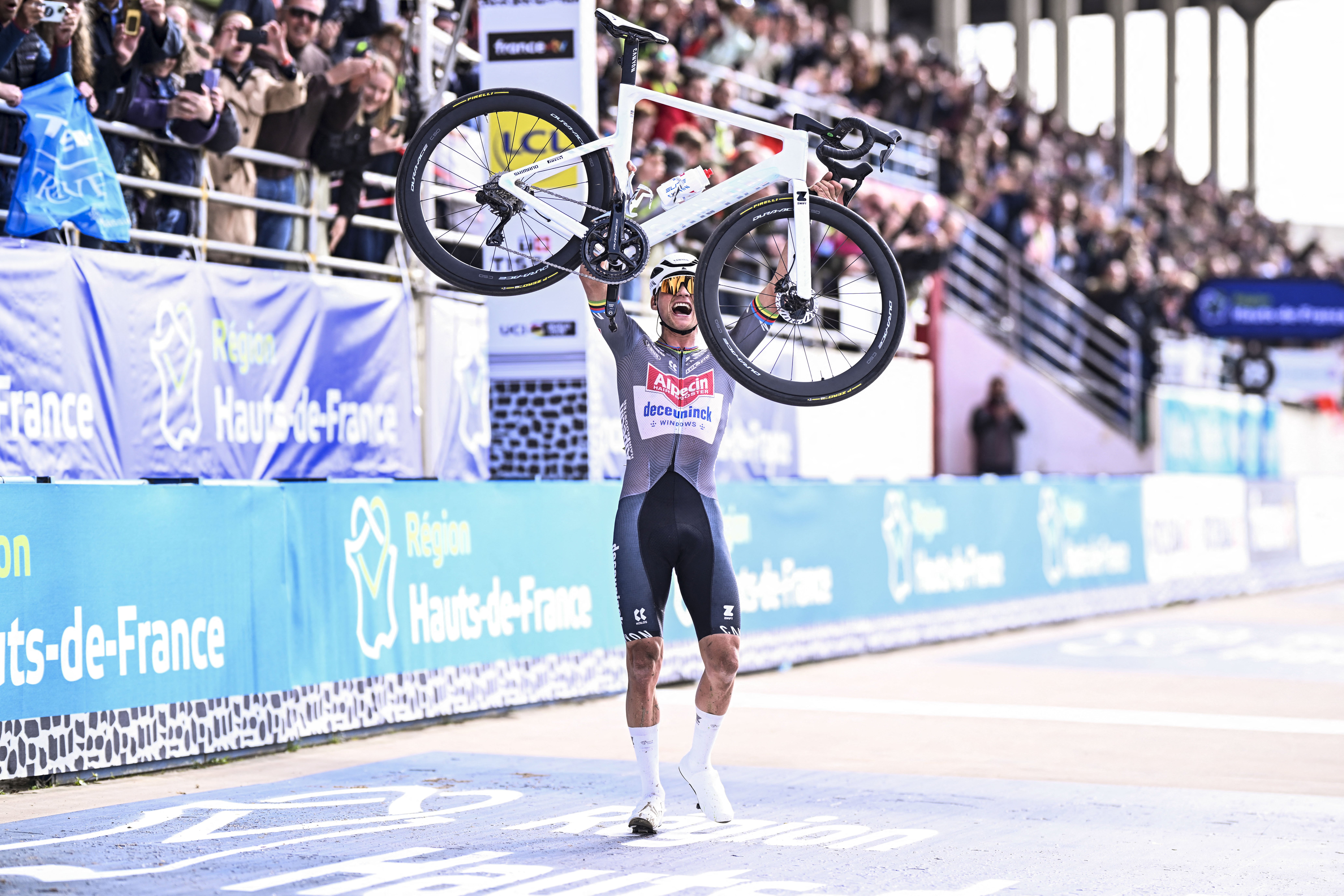 Mathieu van der Poel lifts his bike as he wins Paris-Roubaix 2025