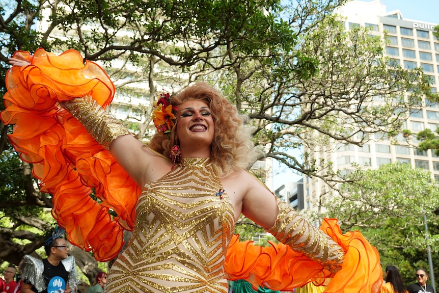 Aurora Arsenic wearing a gold and orange dress.