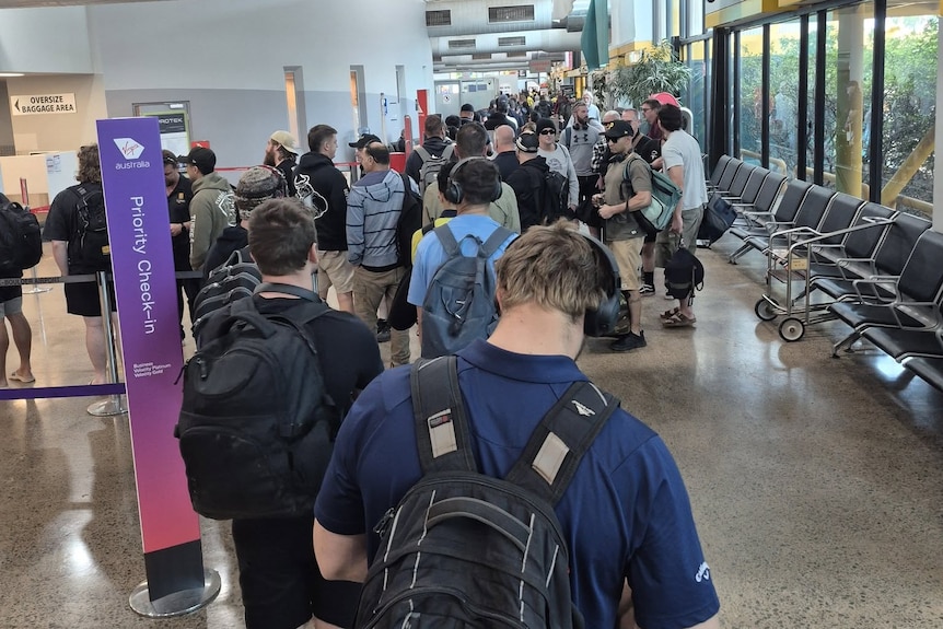 A long line up of passengers at an airport waiting for security screening.  