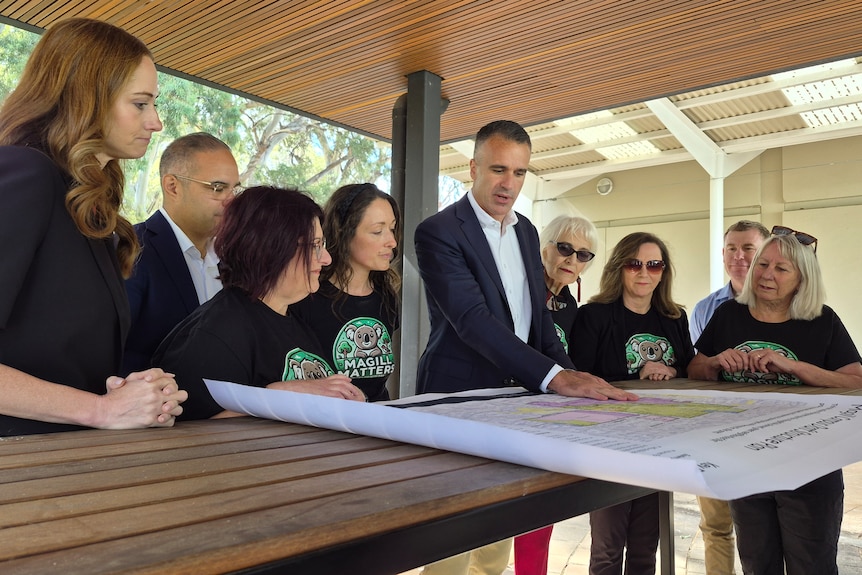 Women and two men look at a map on a table