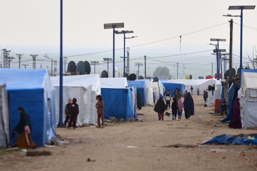 Women and children walk among tents at Al-Roj camp, where thousands of Islamic State group members and their families are held, in the al-Malikiyah area of northeastern Syria, on January 29, 2026.