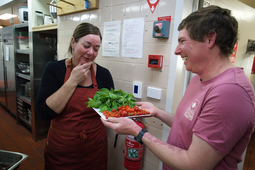 Brooke Hartney and Scott Newman smile while looking at a plate of fresh produce.