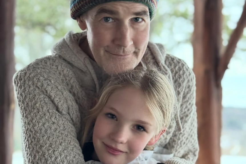 A beanie wearing van der beek holds his blonde daughter 
