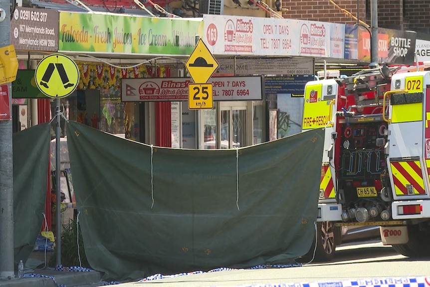 Canvas sheeting hung between pole in shopping strip and fire truck