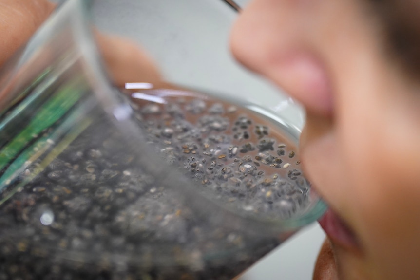 close up woman drinking chia and water out of glass