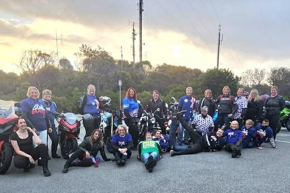 A group of women near their motorbikes. 