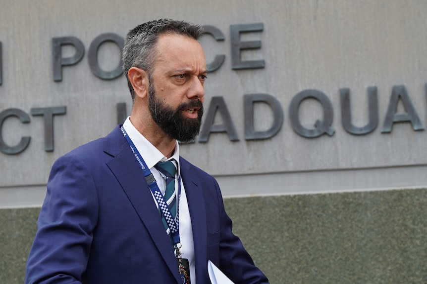 A tall bearded man in business attire speaks to reporters outside a courthouse