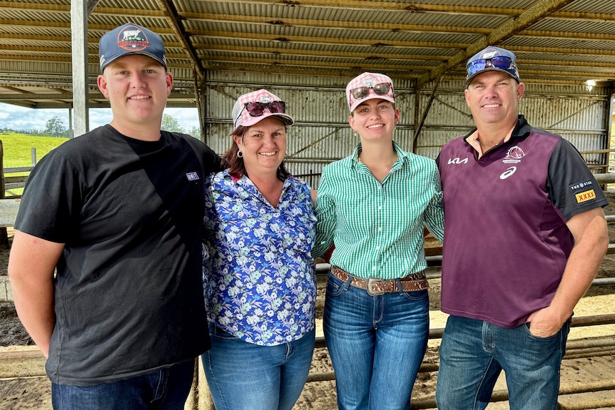 A family smiles at the camera in a shed.