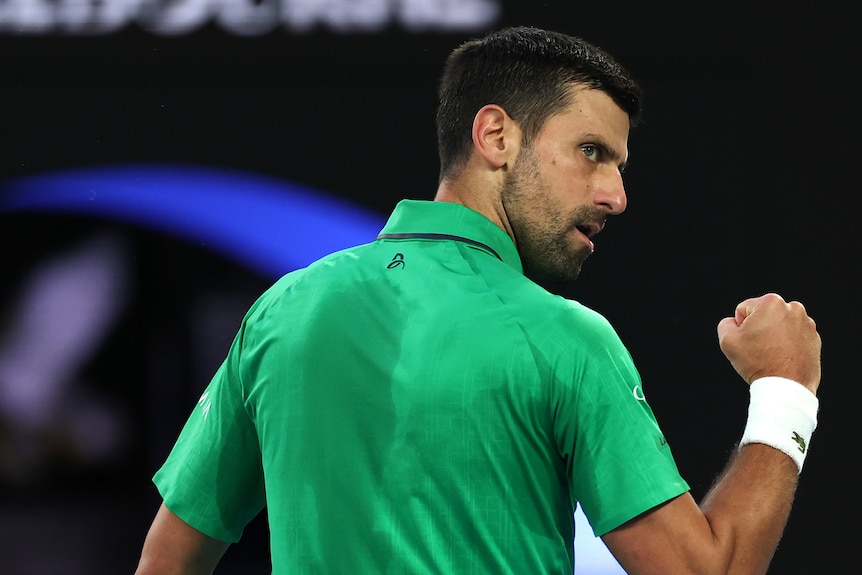 Novak Djokovic looks over his shoulder as he clenches his fist in the Australian Open final.