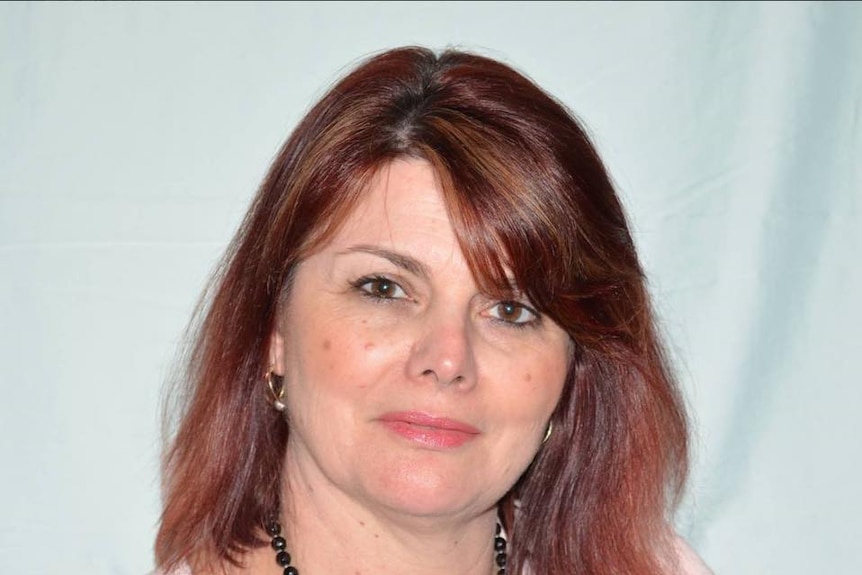 A headshot of a woman with red hair, against a white background.