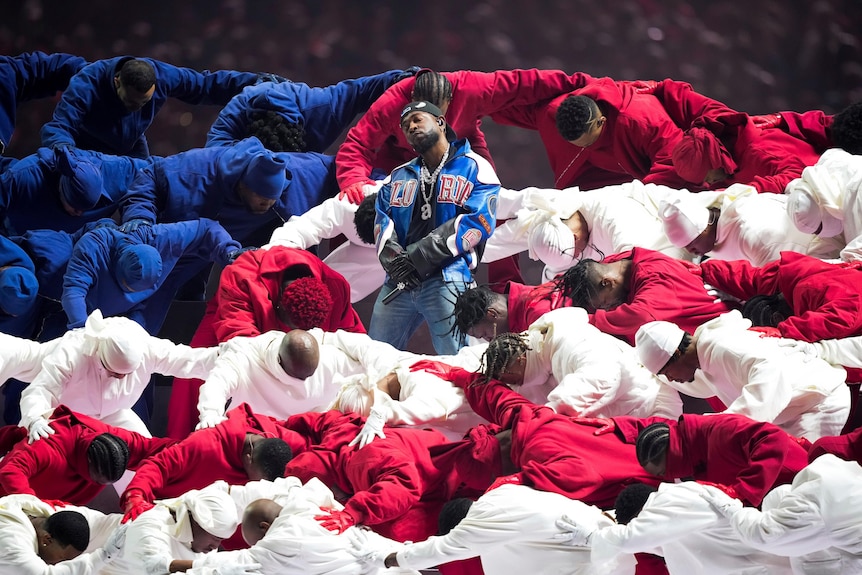 Artist standing among dancers dressed in red, white, blue during the half-time show