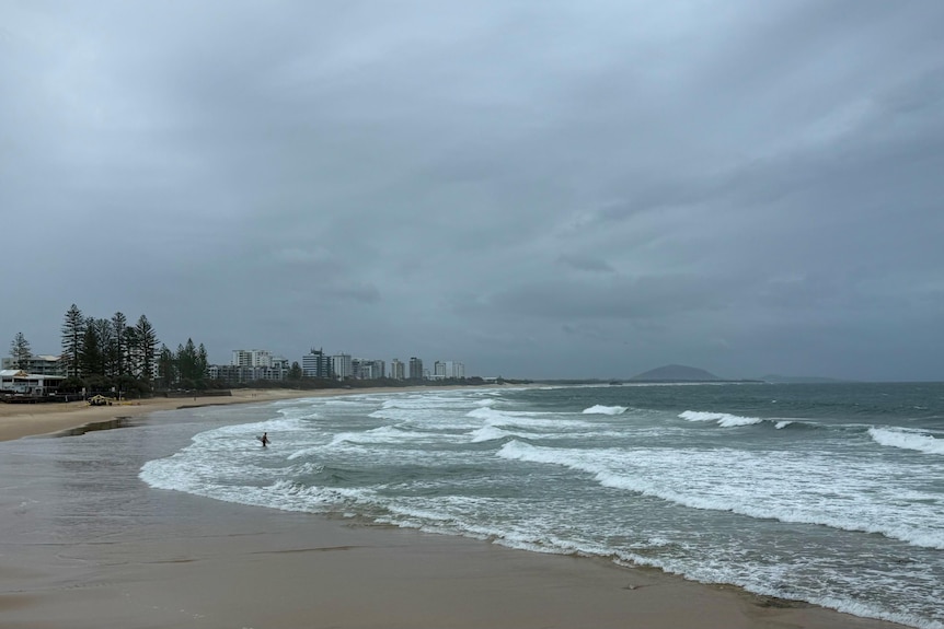 Stormy clouds over a beach with a few surfers in the water