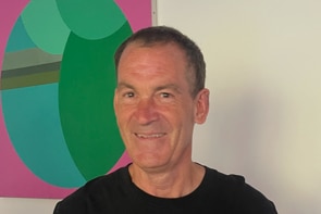 A man wearing a Midnight Oil Tshirt and standing in front of artwork