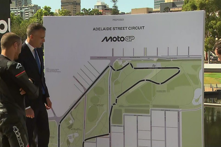Three men stand around looking at a street circuit map.