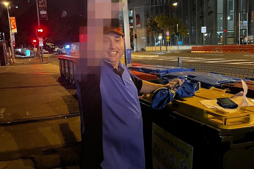 Man standing next to bins in city street with his hand pixelated 