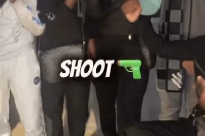 A cropped screenshot with a group of teenagers and the word 'Shoot' with a gun emoji next to it. 