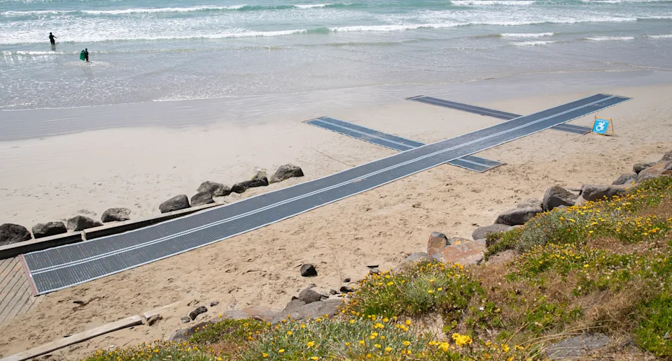 Blue beach matting on the sand from the path to the edge of the ocean.