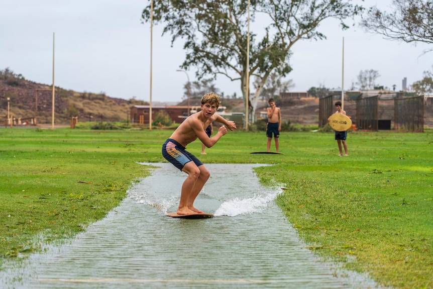 kids in the water with wakeboards on a cricket pitch