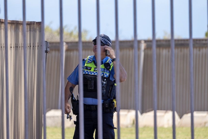 A police officer at the protest site standing behind a gate.