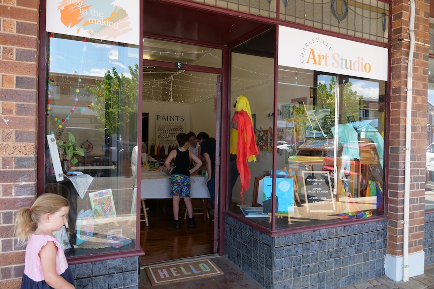 A young girl standing outside a shop. 