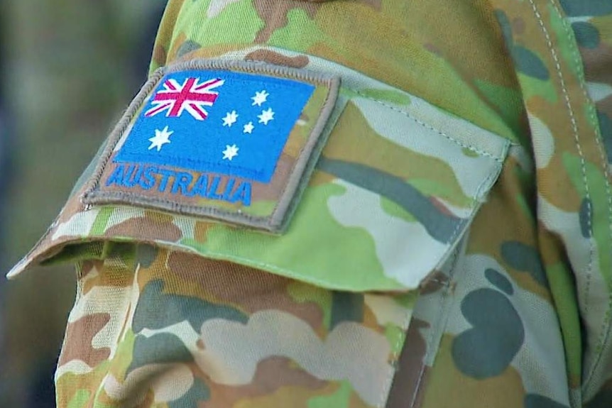 A close-up of an Australian Army patch and an Australian flag patch on an ADF officer's uniform.