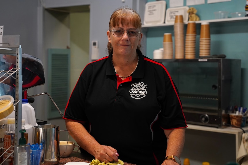 A woman wearing a black polo shirt in a cafe