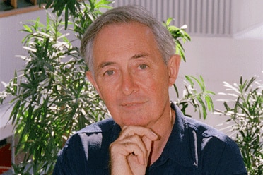 Dr Lowe sitting down next to a few plants on a baclony.