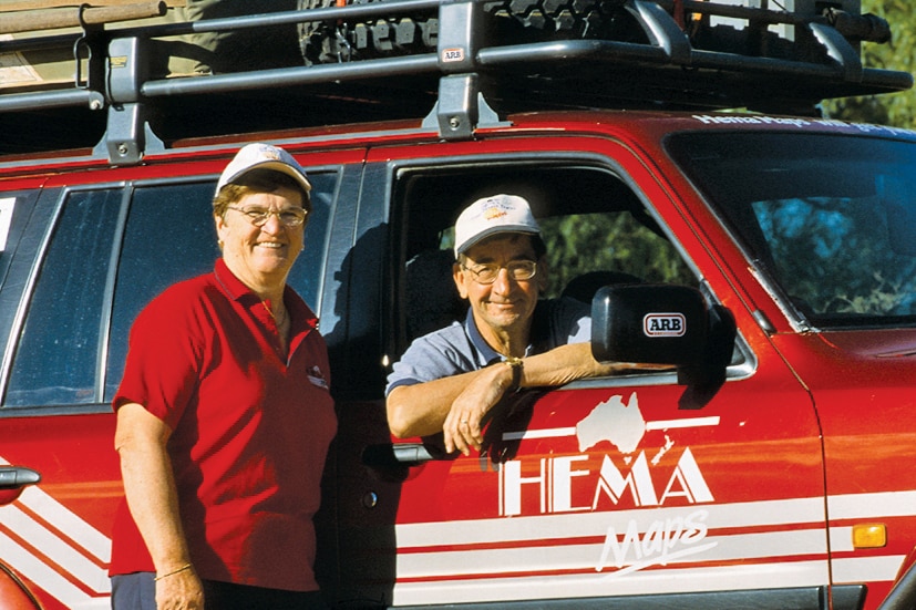A man and woman stand in front of a branded 4WD vehicle.