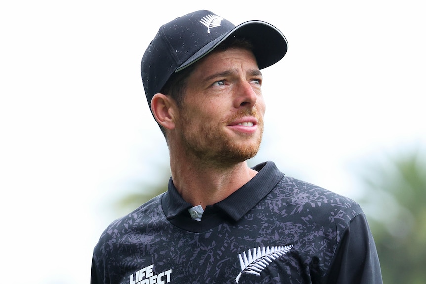 Mitchell Santner wearing a hat and looking upwards