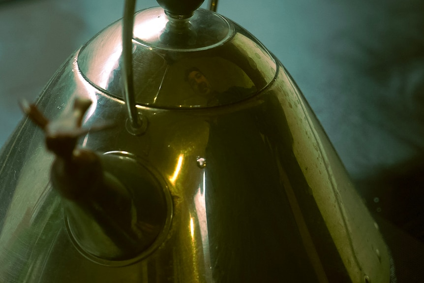 Man's reflection in kettle