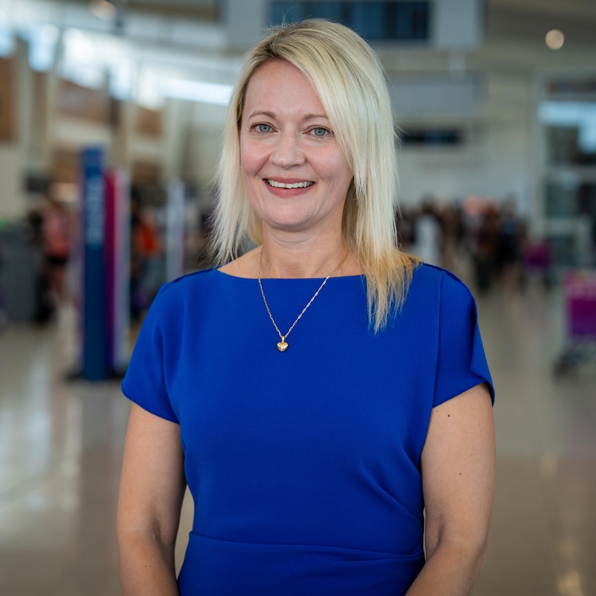 A woman with blonde hair wearing a blue dress at an airport