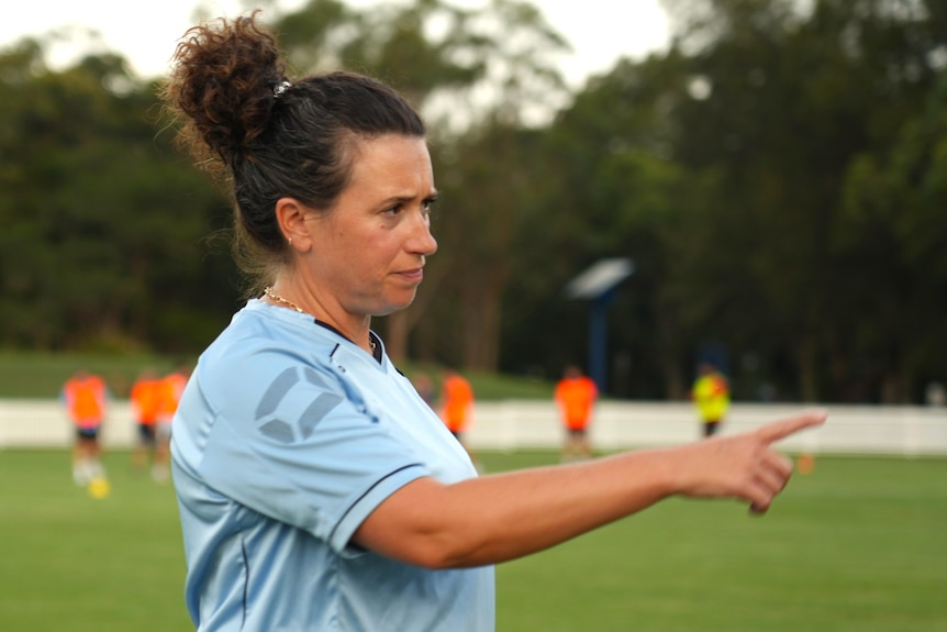 A female footballer in her 40s points during a training session
