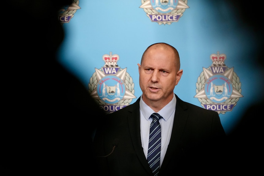 WA Police Detective Acting Superintendent Eamon Flanagan speaking at a media conference indoors with shadows either side.
