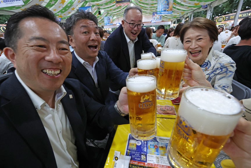 People toast with beer glasses at a beer garden in Sapporo, Japan