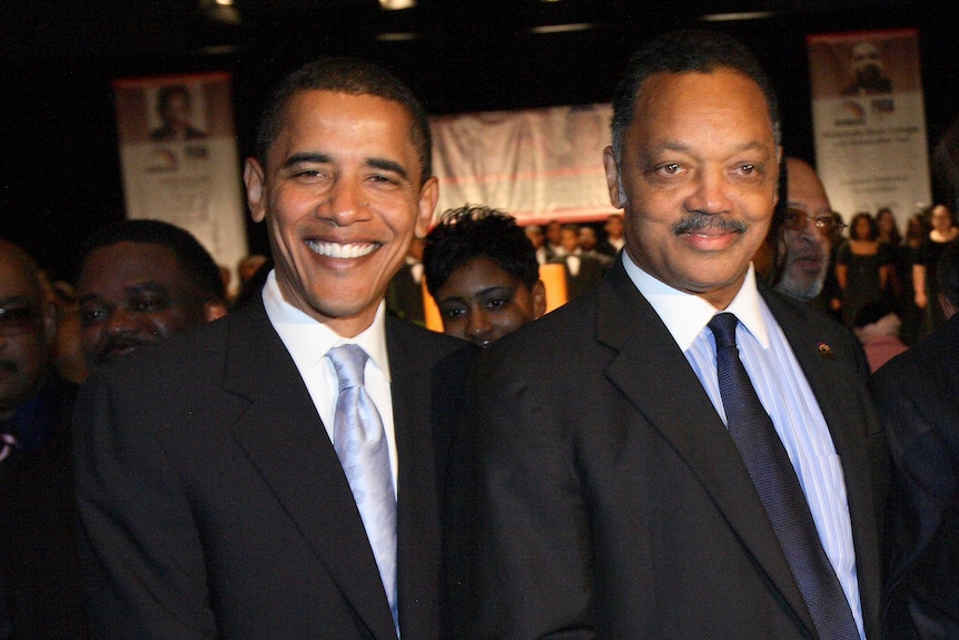 Barack Obama and Jesse Jackson pose for the cameras, both dressed in suits and smiling