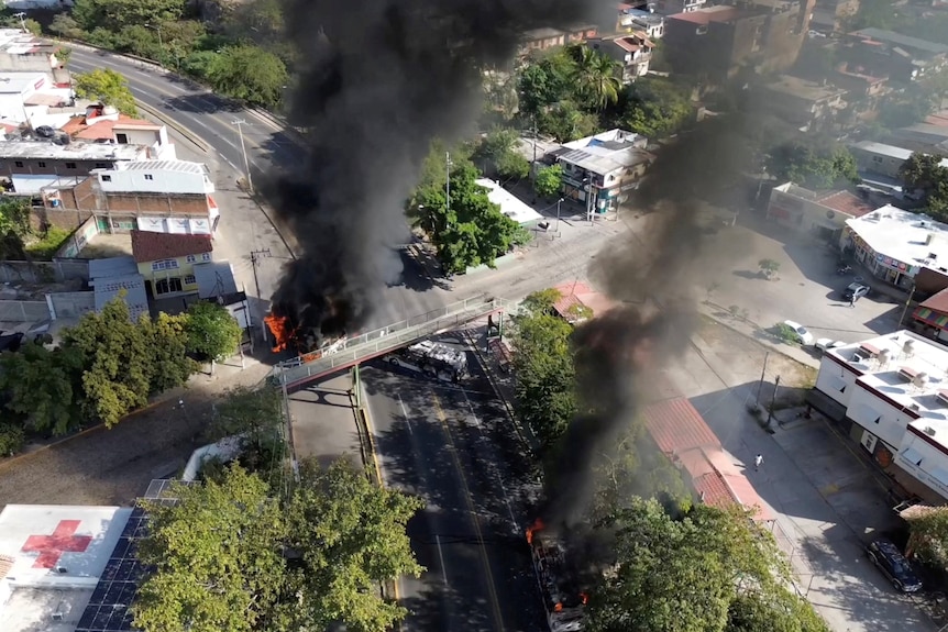 Large black plumes of smoke billowing upwards from car fires on roadways snaking through buildings.