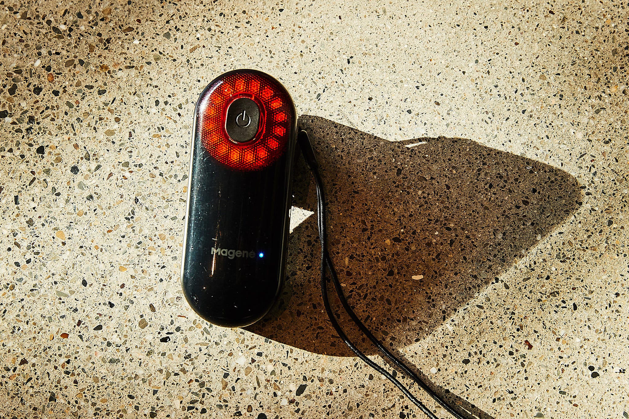 Device with a circular light pattern on top, resting on a textured surface.