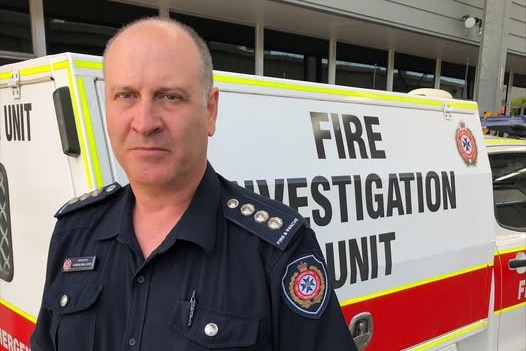 A fireman in uniform in front of a truck.