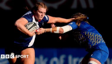 Sophie Barrett of the Wolfhounds hands off an opponent with the ball under one arm