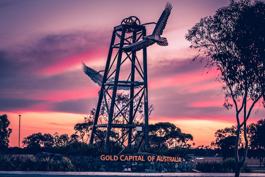 A photograph of a sign at Kalgoorlie-Boulder Airport taken at sunset claiming the city as Australia's gold capital.   