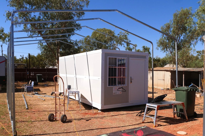A small demountable sjhed in a dusty yard on a country property.